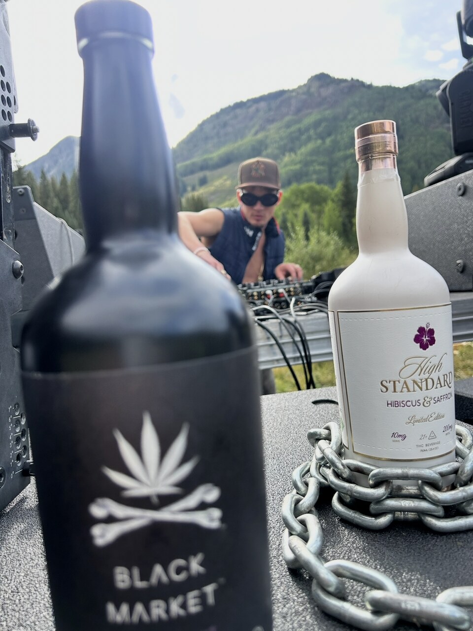A close-up of a Black Market bottle beside a High Standard bottle, with a person at the mixing table behind them.